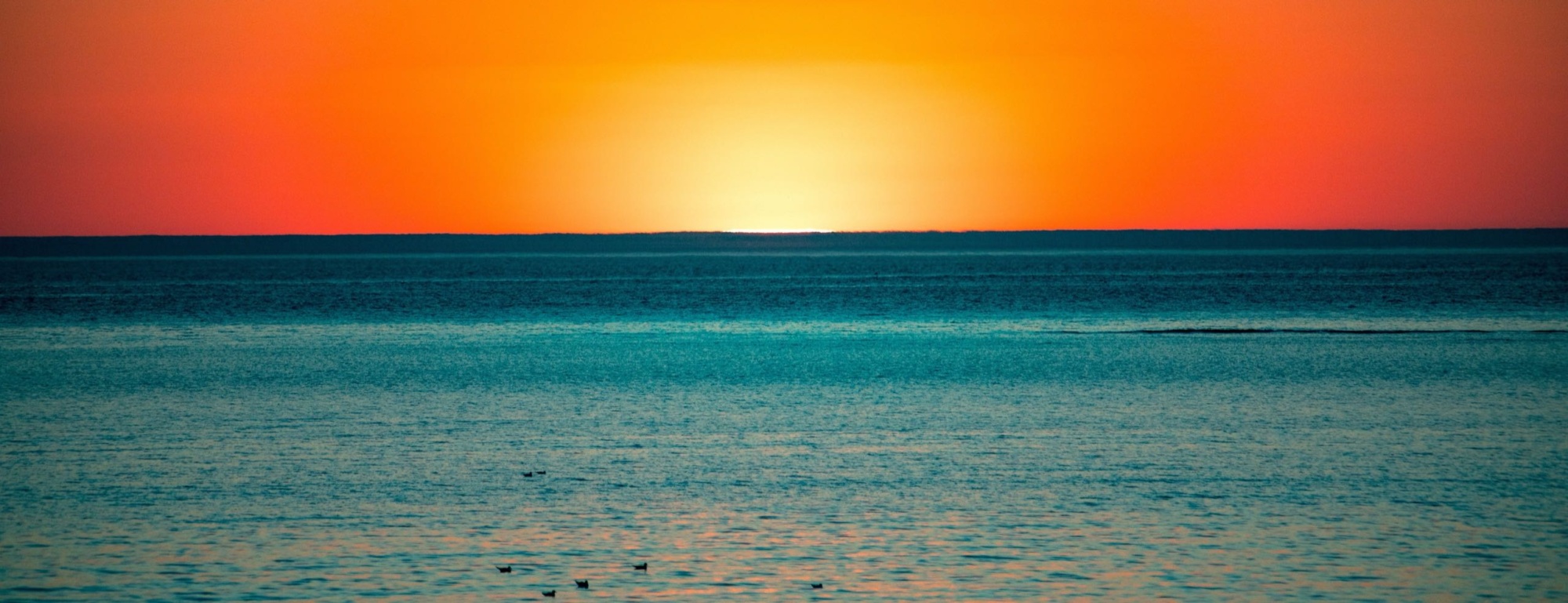 Coucher de soleil sur une mer calme, horizon dégagé